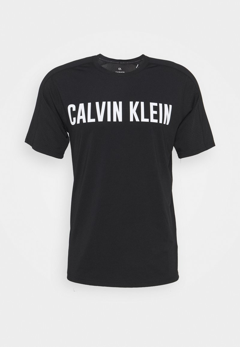 Černé tričko s krátkým rukávem s velkým bílým nápisem "CALVIN KLEIN" na prsní části a kulatým výstřihem.