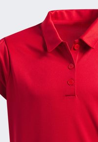 Czerwona koszulka polo z kołnierzykiem, trzema dopasowanymi guzikami, gładką teksturą, z krótkimi rękawami i dopasowanym krojem.