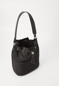 Czarna torba typu bucket wykonana z nylonu, z zamknięciem na sznurek, bocznymi kieszeniami i długim, regulowanym paskiem. Gładka tekstura, minimalistyczny design.