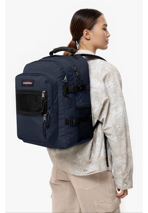 Tummansininen Eastpak-reppu, jossa on useita vetoketjullisia taskuja, verkkoakselit ja säädettävät hihnat, tyylikäs suorakulmainen muotoilu.