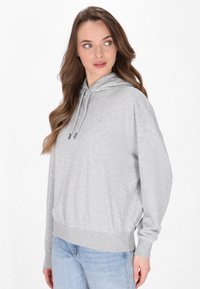 Hanorac gri deschis cu o potrivire lejeră, snururi ajustabile și manșete și tiv cu textură ribbed. Țesătură moale, design casual.