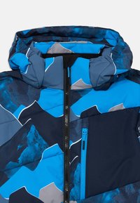 Jachetă puffer albastră cu un model geometric inspirat de munți, în nuanțe de albastru și gri, dotată cu un buzunar cu fermoar pe piept și glugă ajustabilă.