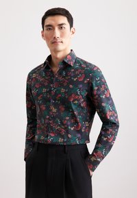 Camicia floreale verde scuro, con vari fiori e foglie colorati. Maniche lunghe, design con bottoni e colletto a punta.