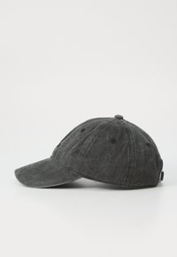 Caciulă din bumbac negru, cu o vizieră curbată, material texturat, nasture superior și orificii de ventilație. Curea ajustabilă în spate.