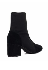 Bottines en daim noir avec un bout arrondi et un talon carré. Présentent un design sans couture et une texture lisse, avec des détails de couture minimaux.