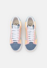 Zapatillas multicolores que presentan una mezcla de pana y tejidos lisos en azul, rosa y amarillo. Cierre con cordones blancos y suelas de goma.