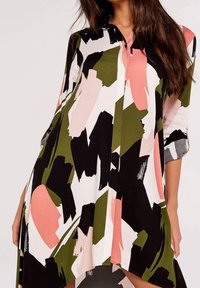 Košile na knoflíky s výrazným abstraktním vzorem v zelené, růžové, černé a bílé barvě. Má tříčtvrteční rukávy a volný střih.