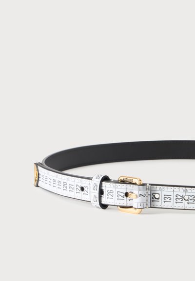 Ceinture blanche avec imprimé mètre ruban noir, boucle dorée gravée de "Moschino," et passant de ceinture noir sur un fond clair uni.