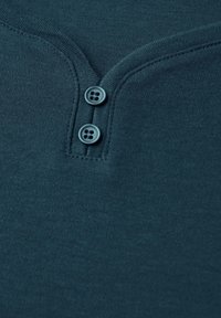 Tissu vert foncé avec une texture lisse, doté d'un col henley et de deux boutons assortis à la patte de boutonnage.
