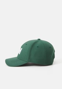 Zöld, textilből készült baseball sapka ívelt viselhető csúccsal. Az elülső részen egy fehér "H" betű található, és hat szellőzőlyuk van rajta.