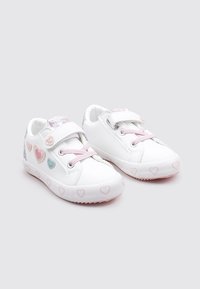Zapatillas blancas con detalles en rosa, con un patrón de corazones, cierre de velcro y cordones. Fabricadas con material sintético y con una superficie texturizada.