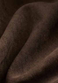 Tissu texturé marron avec une surface douce et lisse, présentant des variations subtiles de nuance et de densité, créant une apparence riche.