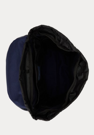 Μπλε σακίδιο με μαύρο κορδόνι στο άνοιγμα, που δείχνει το άδειο κύριο διαμέρισμα και την υφασμάτινη επένδυση στο εσωτερικό.