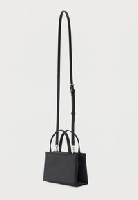 Μικρή ορθογώνια μαύρη τσάντα χειρός με δύο κοντές λαβές και ρυθμιζόμενο μακρύ ιμάντα ώμου, πάνω σε λευκό φόντο.