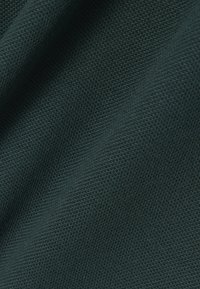 Dunkelgrüner strukturierter Stoff zeigt ein feines Webmuster, das seine Weichheit und Haltbarkeit hervorhebt. Das Material wirkt glatt und geschmeidig.