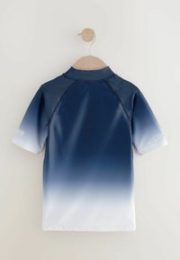 Marinblå kortärmad rash guard med en gradienteffekt som övergår i vitt vid fållen. Har en hög krage och platta sömmar.