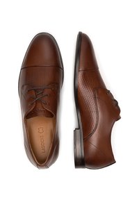 Hnedé kožené topánky s textúrovanou bočnou panelou a hladkým prstom. Majú šnurovanie a elegantnú gumovú podrážku.