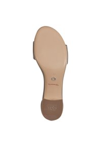 Semelle de sandale à talon haut beige avec caoutchouc texturé pour une meilleure adhérence, nom de la marque en relief et accent métallique circulaire près du talon.