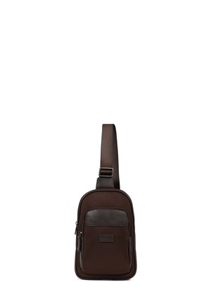 Petit sac bandoulière marron foncé avec sangle ajustable, poche zippée à l'avant et panneau d'accent en cuir.