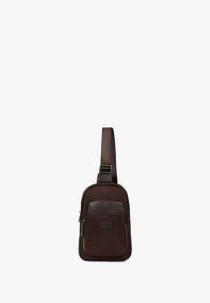 Petit sac bandoulière marron foncé avec sangle ajustable, poche zippée à l'avant et panneau d'accent en cuir.