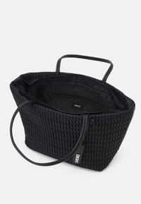 Sac fourre-tout texturé noir DKNY avec deux anses, ouverture supérieure montrant une poche intérieure zippée et une doublure de marque.
