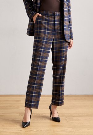 Navy geruite broek met een bruine checkprint, gemaakt van een gestructureerde stof, met een getailleerde pasvorm en zijzakken. Gecombineerd met zwarte hakken.