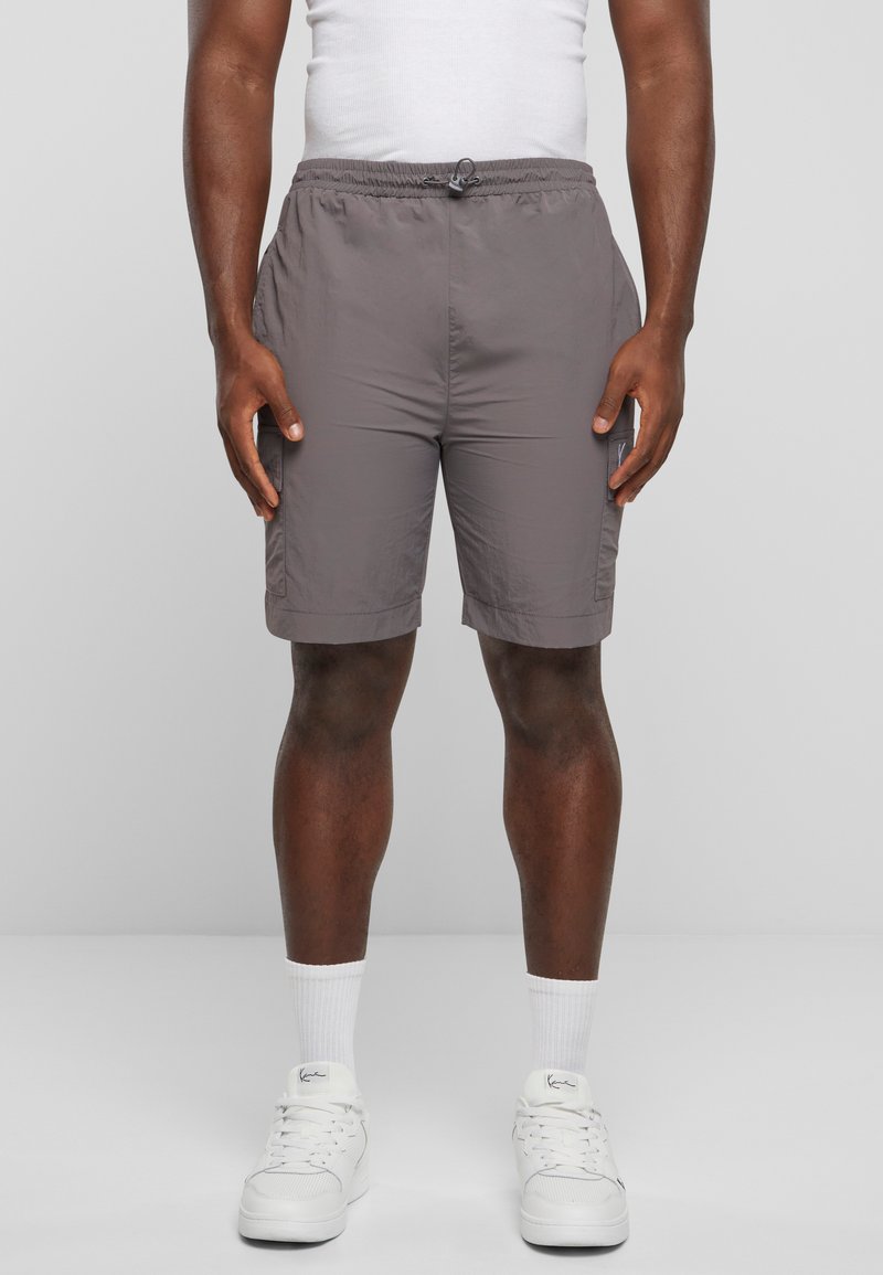 Shorts gris légers avec une taille élastique et un cordon de serrage. Comprend des poches latérales et une coupe droite, associés à des baskets blanches.