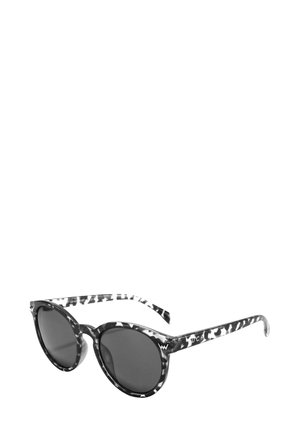 Schwarz-weiß gepunktete Sonnenbrille mit runden Gläsern, dünnen strukturierten Bügeln mit einem markanten Muster, dunkelgrauen Gläsern und prominentem Markenlogo.