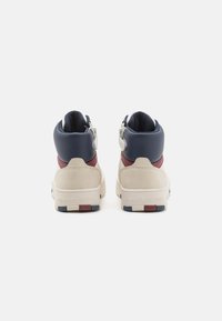 Sneaker alte con colletto in pelle blu navy, corpo in suede beige e dettagli rossi. Comprendono una cerniera laterale e una suola in gomma testurizzata.