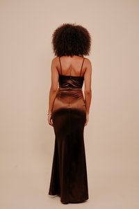 Brązowa satynowa sukienka z dopasowanym gorsetem i rozkloszowanym dołem. Charakteryzuje się cienkimi ramiączkami i ozdobnym szwem z tyłu. Gładka tekstura i błyszczące wykończenie.