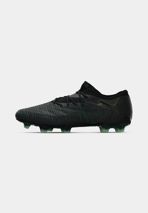 Črne nogometne kopačke Puma z teksturirano zgornjo plastjo, vezalkami in kramljivimi konicami v zeleni odtenek, zasnovane za igro po trdi površini.