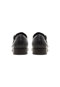 Zapatos de cuero negro con un acabado suave, punta redondeada y detalle de hebilla en la parte trasera. Presentan un tacón ligeramente apilado para mayor elevación.