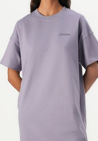 Fialové oversized tričko vyrobené z bavlněné směsi, s kulatým výstřihem, krátkými rukávy a malým textovým logem u hrudi.