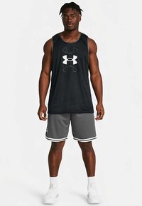 Černý tílko z síťoviny s bílým logem, doplněné šedými sportovními šortkami s bílým lemem. Obuv tvoří bílé tenisky.