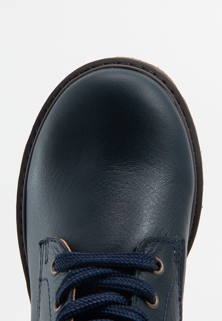 Marineblaue Lederschuhe mit runder Zehenform, strukturierten Oberflächen und brauner Naht. Mit marineblauen Schnürsenkeln und Ösen für sicheren Halt.