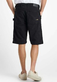 Zwarte cargo shorts met meerdere zakken, stevig materiaal en een relaxed fit, met een riemlus en een detail van een achterzak.
