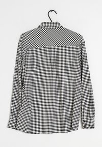 Svartvit rutig skjorta med lång ärm och krage, med knappstängning fram och justerbara manschetter. Texturerad tygdetalj synlig.