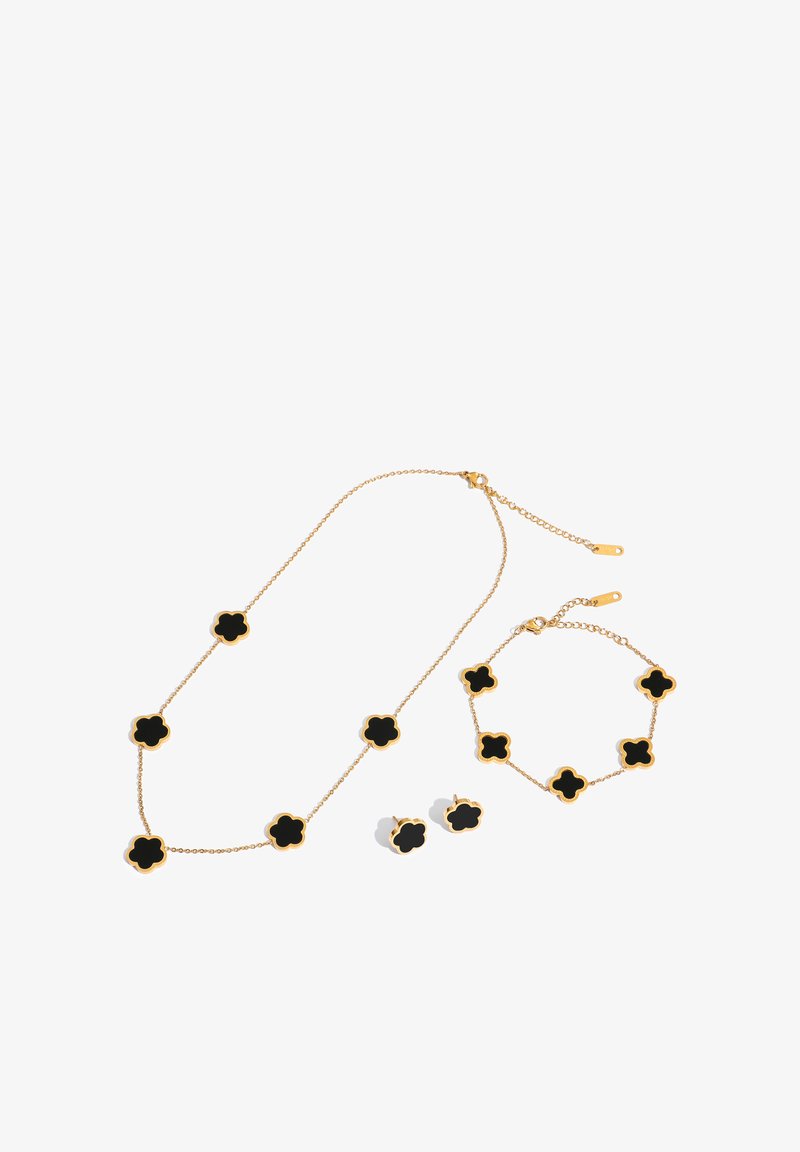 Gold jewelry set with black clover-shaped inlays, including a necklace, bracelet, and a pair of stud earrings on a white background.