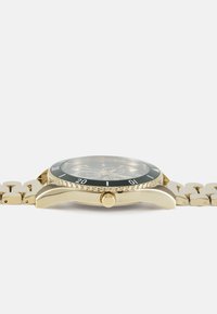 Montre dorée avec un bezel noir, dotée d'un cadran rond, d'accents argentés et d'un bracelet en métal à maillons. L'affichage comprend des chiffres et des marqueurs.