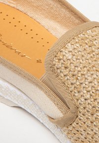 Geweven beige instap schoen met gouden accenten, een gevoerde binnenzool en crème stoffen rand. Textuur oppervlak met kleine perforaties op de binnenzool.