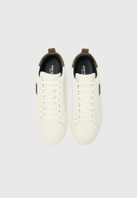 Weiße Ledersneaker mit runder Zehenform, geschnürtem Vorderteil, olivgrünen Akzenten an der Ferse und einem gepolsterten Innenraum in Schwarz. Ein schwaches Markenlabel ist sichtbar.