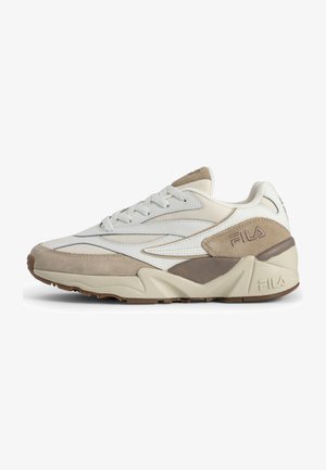 Zapatilla deportiva en blanco y beige con un upper de ante y malla, puntera redondeada, suela gruesa y acentos elevados que presentan el logo de Fila.