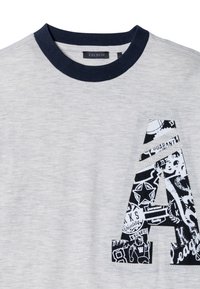 T-shirt grigia con collo blu navy che presenta una grande lettera 'A' in stampa grafica bianco e nero, che mostra vari motivi e design.