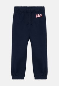 Námornícke modré detské teplákové nohavice s elastickým pásom, šnúrkou na stiahnutie, zbernými manžetami a červeným logom "GAP" na ľavom boku.
