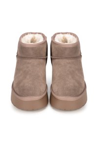 Botines de ante marrón con suave forro blanco, punta redondeada y suela de goma beige. Presentan costuras mínimas y sin hardware visible.