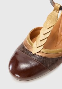 Scarpa con tacco alto marrone e oro con punta tonda, accento in pelle intrecciata e motivo a pois testurizzato sul corpo. Finitura liscia.