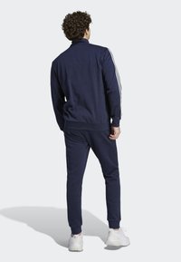 Mornarski trenirka napravljena od mekanog materijala, s bijelim bočnim trakama. Jakna ima ovratnik, dok hlače imaju elastične manžete i pojas.