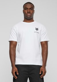 Hvid bomulds t-shirt med et lille sort Zoo York-logo på venstre bryst, med korte ærmer og rund halsudskæring.