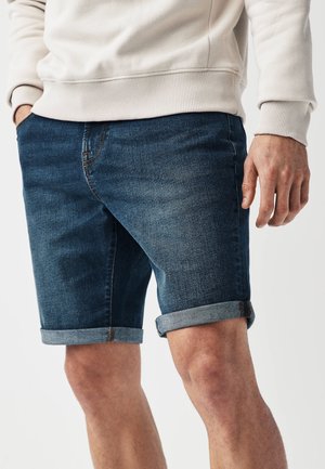 Jeansshorts i mörkblått, med en klassisk skärning och uppvikta fållar, subtila blekningar och en framficka för förvaring.