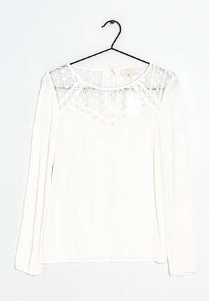 Witte blouse met lange mouwen, voorzien van een doorschijnend kanten paneel bij de halslijn en een gestructureerde stof. Rondom afgeronde zoom en haaksluiting aan de achterkant.